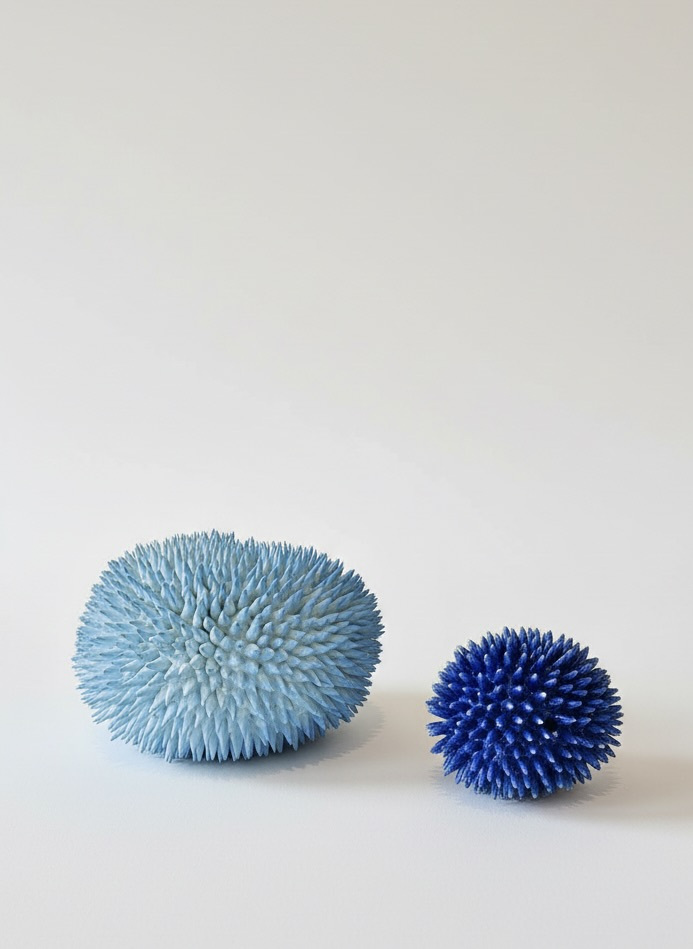 Two blue ceramic masses on a light surface